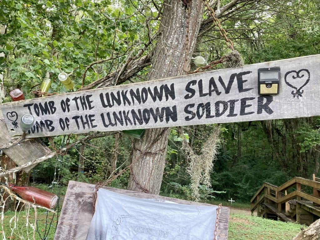 Memorial Park at the bottom of the Edmund Pettus Bridge. The sign reads 'Tomb of the unknown slave. Tomb of the unknown soldier.'