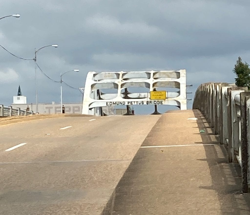 Edmund Pettus bridge peeking over the crest of the road, walking across the Alabama River towards Selma