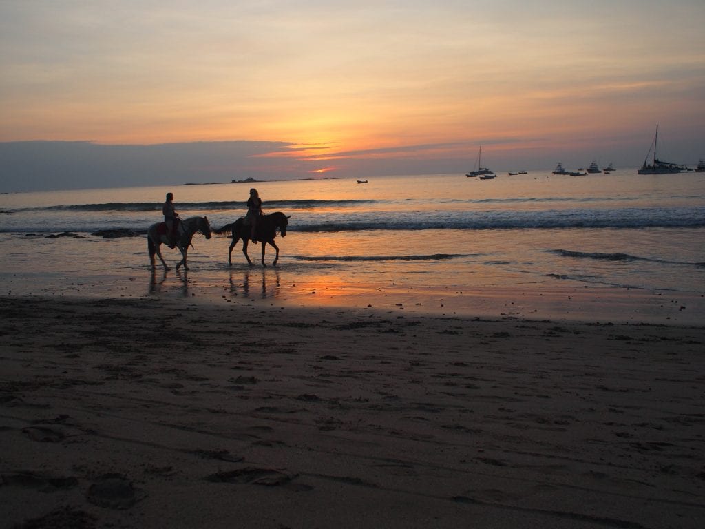 Taking in the sunset with horseriders going past on a Tamarindo beach, Costa Rica
