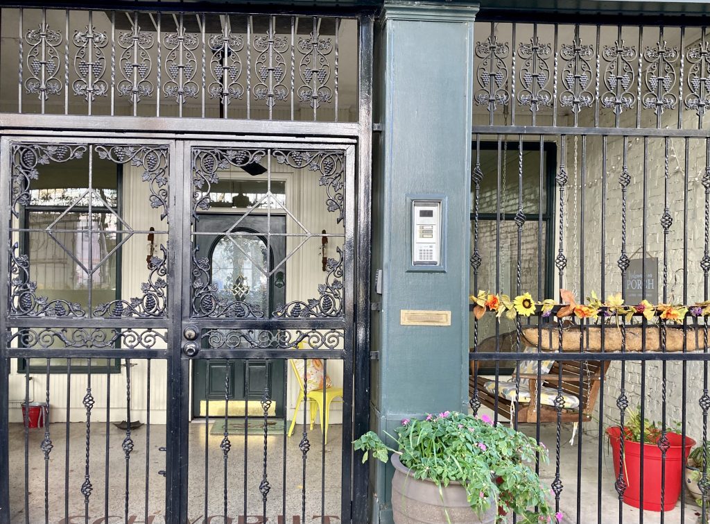 A street porch decorated with flowers and a porch swing behind iron bars in Birmingham, Ala